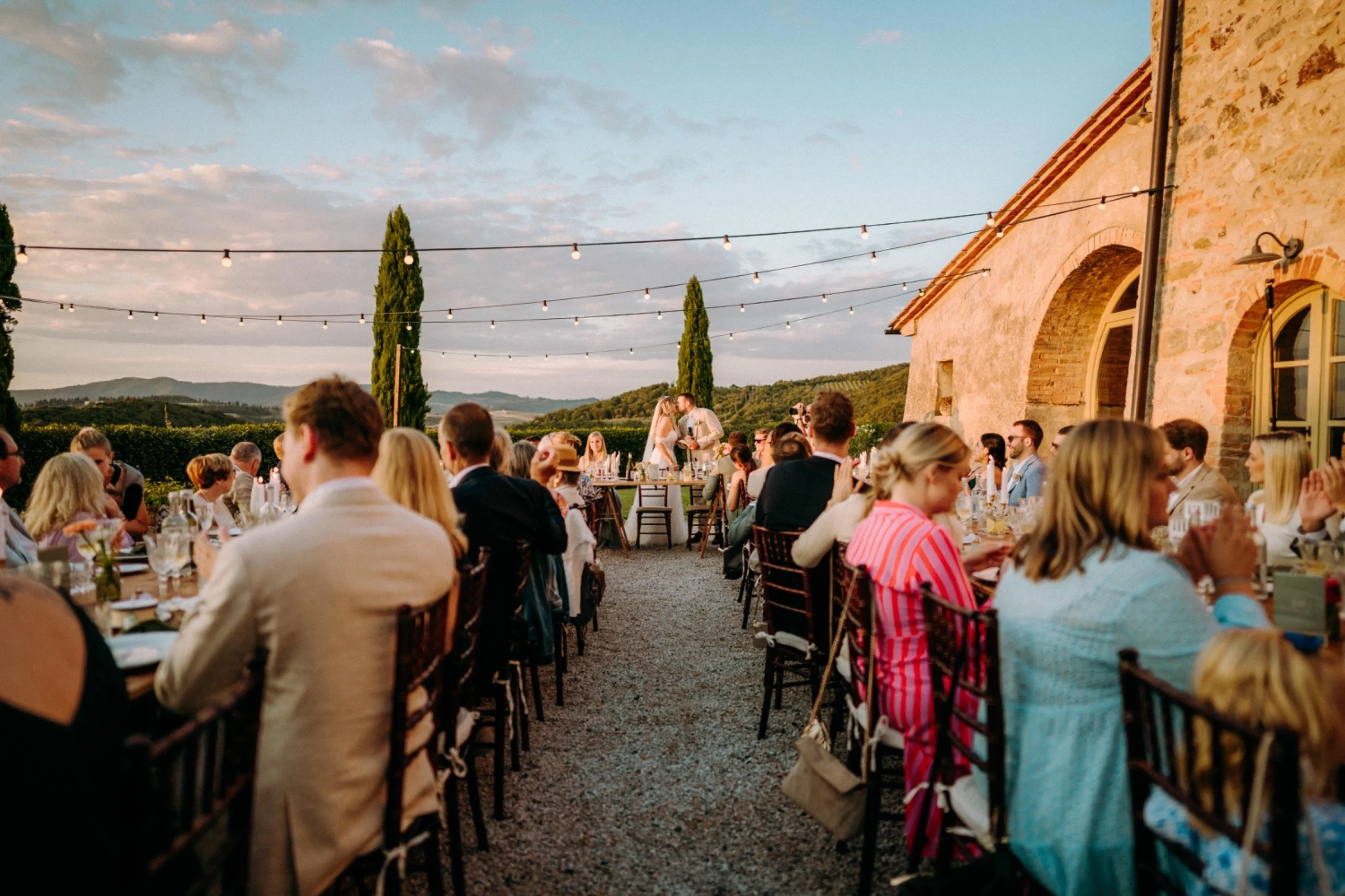 Outdoor wedding dinner with string lights at sunset