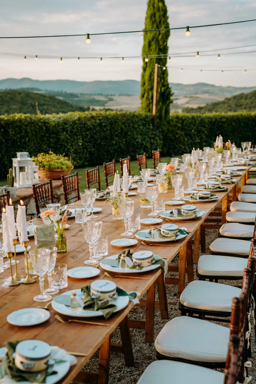 Long wedding table with crystal glasses and candles overlooking Tuscan hills