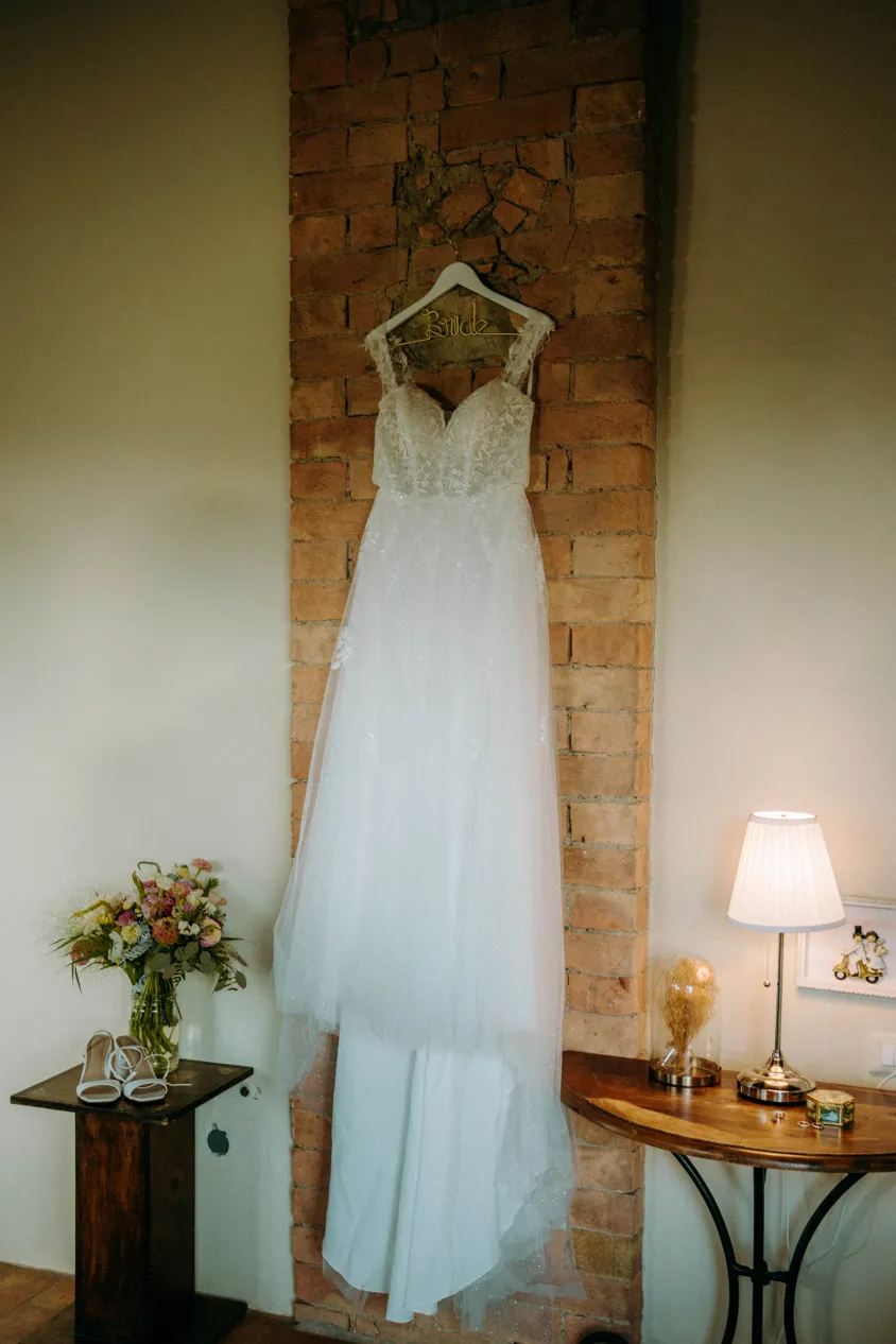 Brautkleid hängt an einer Backsteinwand beim Getting Ready