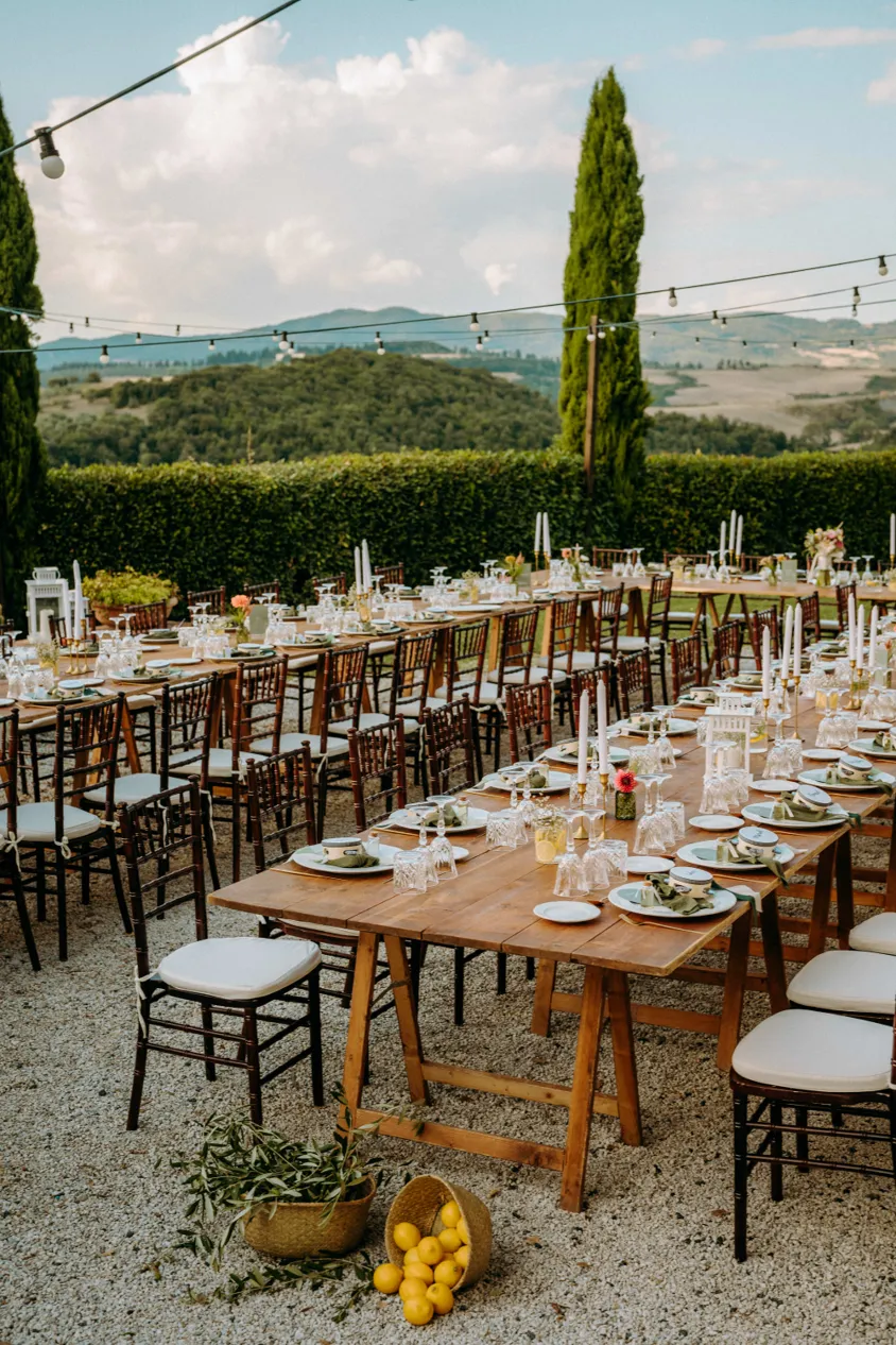 Gedeckte Hochzeitstafeln im Freien mit Zypressen und Hügeln