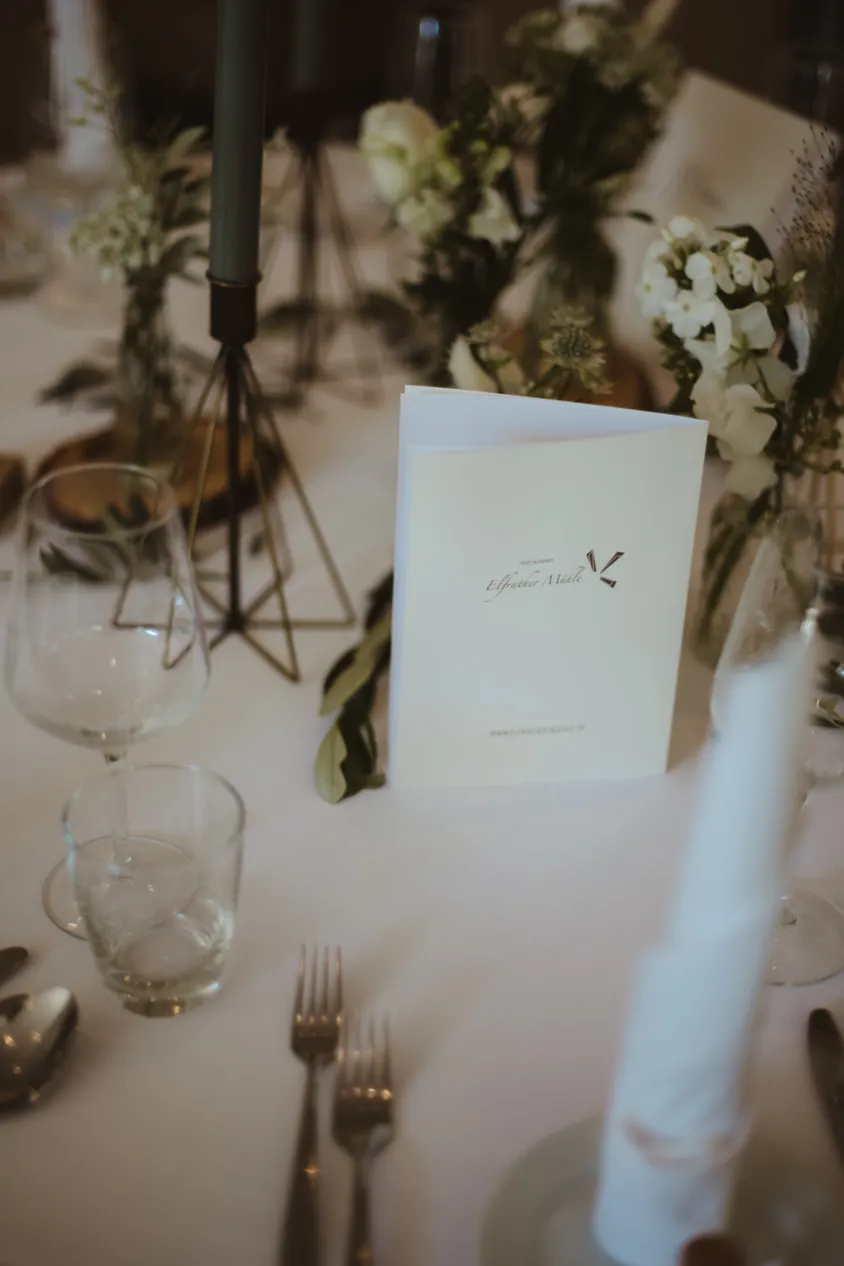 Menükarte auf der Hochzeitstafel mit Kerzen und Blumen