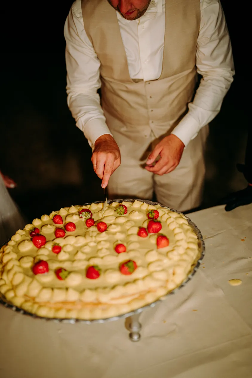 Bräutigam schneidet die Hochzeitstorte mit Erdbeeren am Abend an