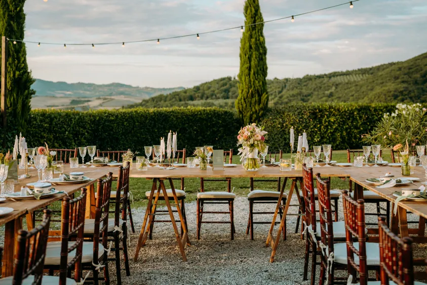 Gedeckte Hochzeitstafel mit Zypressen und Hügellandschaft im Abendlicht