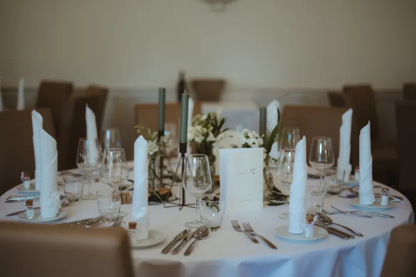 Runde Hochzeitstafel mit weißen Servietten und Menükarte